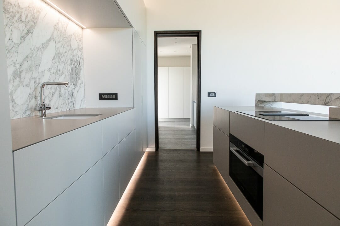 Light cabinetry is accentuated by LED lighting and features marble splashback